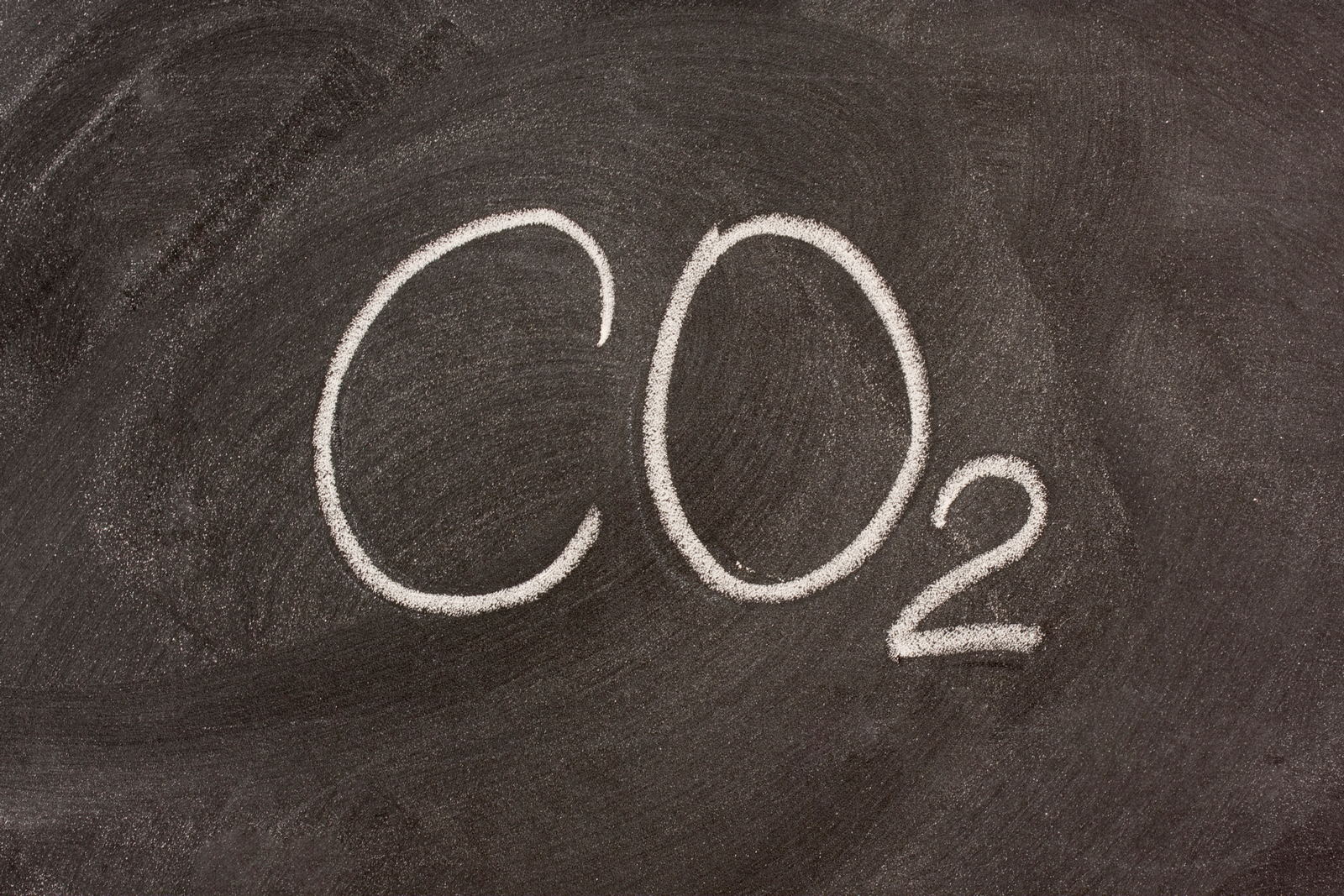 CO2 skrevet med hvitt kritt på sort tavle. Foto.