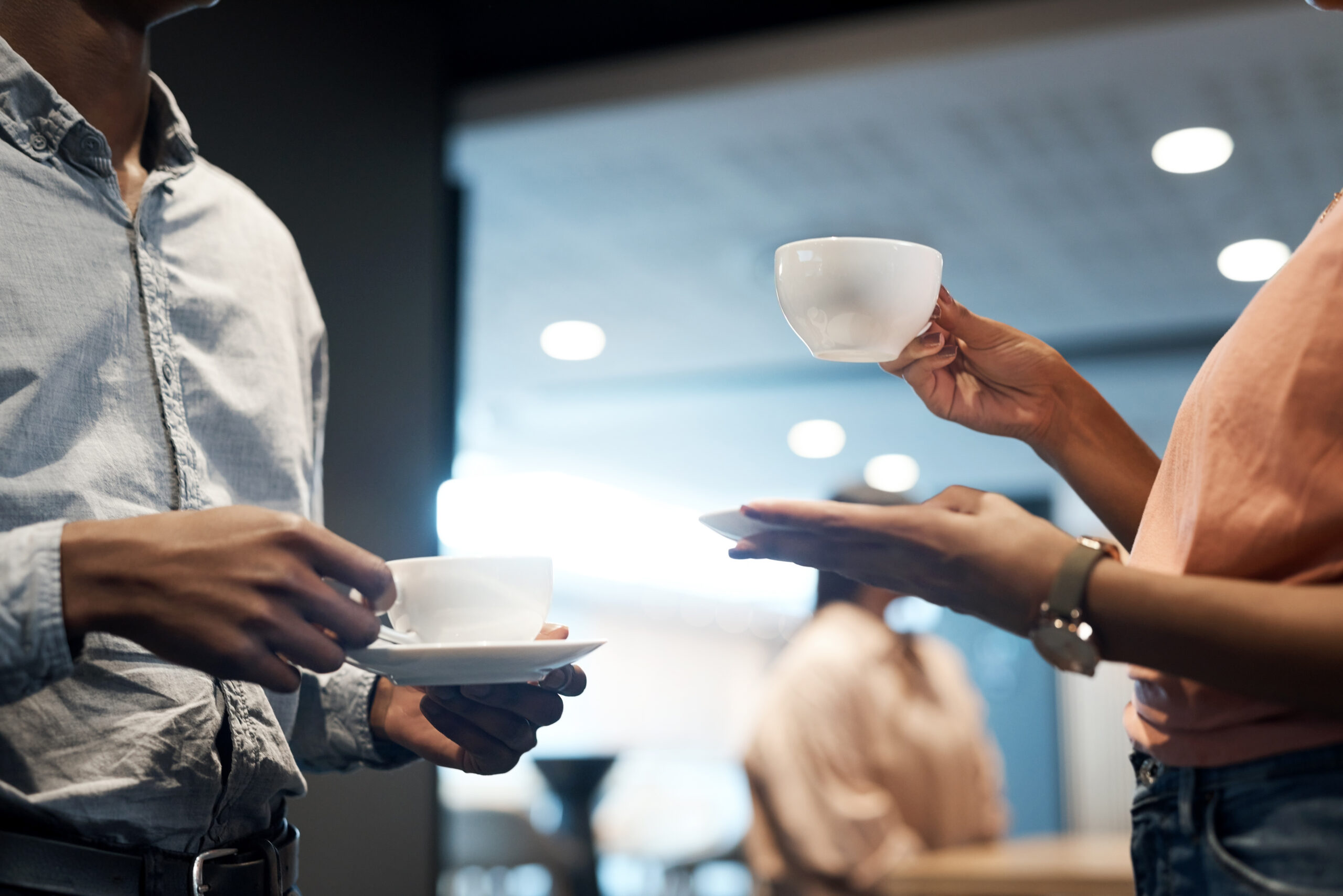 To personer som holder i hver sin kaffekopp. Foto.