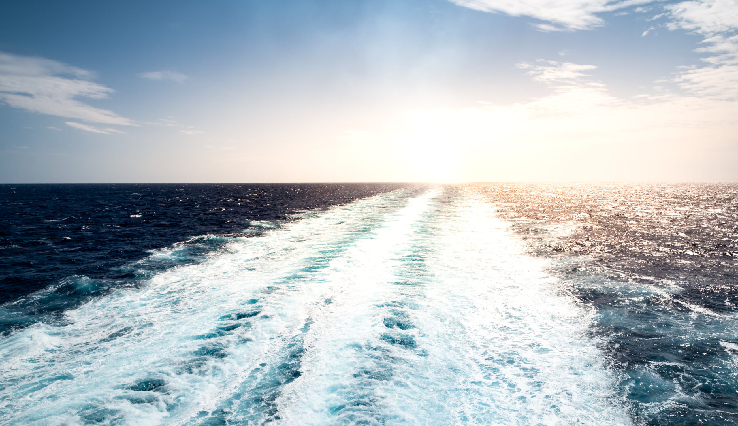 Skummende spor av seilende cruiseskip på Middelhavet en sommerferiedag. Ingen mennesker. Fredelig havlandskap med små bølger, rolig hav og sol. Foto.